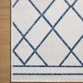 Close-up overhead view of ivory rug corner with diamond lattice details on wood surface