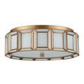 Flush mount ceiling light angled to show soft glowing white diffuser and aged brass details