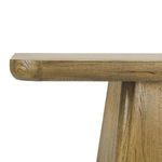 Side close-up emphasizing rounded tabletop edge and texture of trapezoidal pedestal base