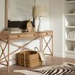 Console styled in a living room with bookshelves, lamp, decorative objects, and a woven basket underneath