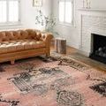 Jocelyn rug styled under a tufted brown leather sofa by white brick fireplace in bright living room