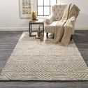 Rug placed in a room setting under a beige armchair and side table on dark hardwood floor