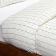 Ivory linen duvet with woven pinstripe design on a wooden bed frame, showing smooth texture and light stonewash finish
