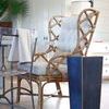 Cecil Drinking Table next to a rattan chair in a bright room setting with wood floors and white walls