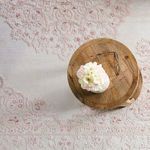 Overhead close-up of rug with wood side table holding flower vase and glasses on medallion