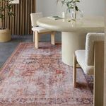 Close interior angle of rug beneath dining table showing worn ornate tribal detail and chair legs