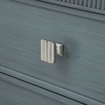 Close-up of polished nickel drawer pull with ridged vertically fluted design on blue wood drawer front