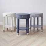 Three Dakota round side tables in white, navy blue, and light gray placed on wood floor against white wall