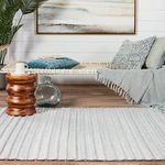 Torre rug shown with woven texture and layered neutral stripes in indoor setting