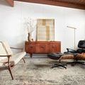 Axel Ocean / Beige Rug styled in modern living room with wooden mid-century cabinet and black leather lounge chair.