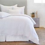 White duvet with subtle ocean blue interwoven stripes and matching shams on a bed with gray headboard