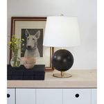 Grant Mini Lamp shown on wooden surface with decorative books, pottery, flowers, and framed dog artwork background