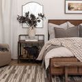 Bedroom rug view near nightstand with woven basket and wall mirror above.