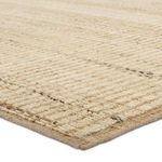 Close-up side view showing low ribbed pile texture and muted taupe tones of the rug edge