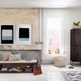 Natural light floods rustic room with paired black and blue tone abstract paintings over wooden bench and patterned rug
