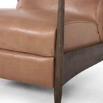 Close-up of warm brown leather upholstery and dark wood frame on recliner backrest