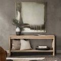 Console table in a styled living room setting with cushions on the shelf and framed abstract art above