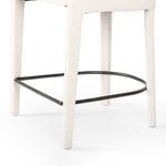 Close-up focused on the metal footrest curve and textured fabric on the stool's legs.