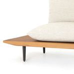 Close detail of wooden frame corner and black metal leg under beige cushion