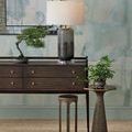 Lifestyle setting of Capella Accent Table beside tapered metal table with plants on woven rug