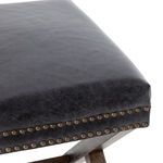 Close-up detail of crossed wooden frame under leather seat with visible wood grain and nailhead trim