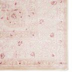 close-up of detailed floral scroll pattern on rug corner in soft pink hues