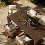 Outdoor dining setting with the table and four cushioned chairs on stone patio