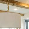 Close-up showing white pleated fabric texture on shade with brass chain in farmhouse kitchen