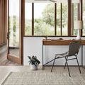 Omen Grey Rug placed in bright room with wooden desk, metal chair, and large windows showing greenery outside