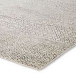 Close-up angled view showing hand-knotted texture and subtle pattern details of ivory and dark gray rug