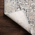 Lucia Grey Mist rug corner lifted to reveal light-colored woven backing on dark hardwood floor