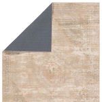 Back side of rug flipped up showing dark gray backing and front vintage medallion pattern