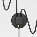 Close-up of black matte wall mount plate and gold accent switch on Onda sconce
