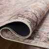 Close-up of folded rug edge revealing thin pile and finely stitched binding in warm tones