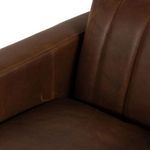 Detail view of leather backrest and part of armrest with vertical stitching lines visible.