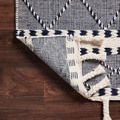 Back side of Sawyer navy rug folded to reveal reverse weave and thick wool fringes