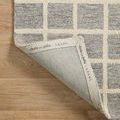 Reverse side of Polly Slate Ivory Rug folded back revealing branded edge and fabric backing