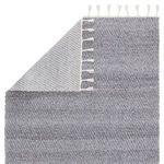 Back side of rug showing lighter woven pattern and tassels folded over corner
