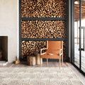 Ehren rug shown in living room setting with stacked firewood and leather chair, angled view