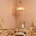 Glenn chandelier lit hanging in styled room corner with rattan chairs and wood side table