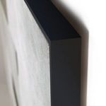 Close-up angled view of sleek black maple frame silhouette on wall-mounted painting