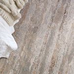 Close-up of rug texture and pattern next to white bedding and cream knit blanket