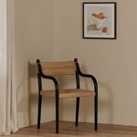 Citrine framed painting hung above black wood chair with woven beige seat and backrest against beige wall