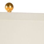 Close-up of antique gold leaf finial topping white lamp shade