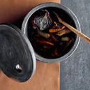 Top view inside Hazel Serving Bowl with roasted vegetables and wooden fork, lid placed beside it