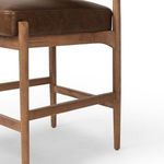 Close-up of brown leather seat cushion with oak frame and footrest in warm wood finish