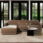 Front view of Bryn sectional styled with round black coffee table and outdoor garden backdrop