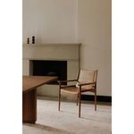 Remy Dining Chair styled in a minimalist dining room, placed near a wooden table and fireplace.