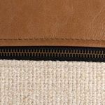 Extreme close-up showing zipper teeth and linen weave texture beneath leather panel