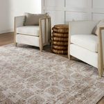 Close view of rug with armchairs and rattan side table, showing pile and light sheen in natural light